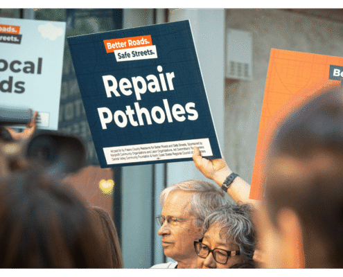 Advocate of Better Roads Safe Streets holds up a sign "Repair Potholes" outside of the Fresno County Elections Office during press event announcing the submission of over 32,000 signatures to advance transportation measure toward November ballot