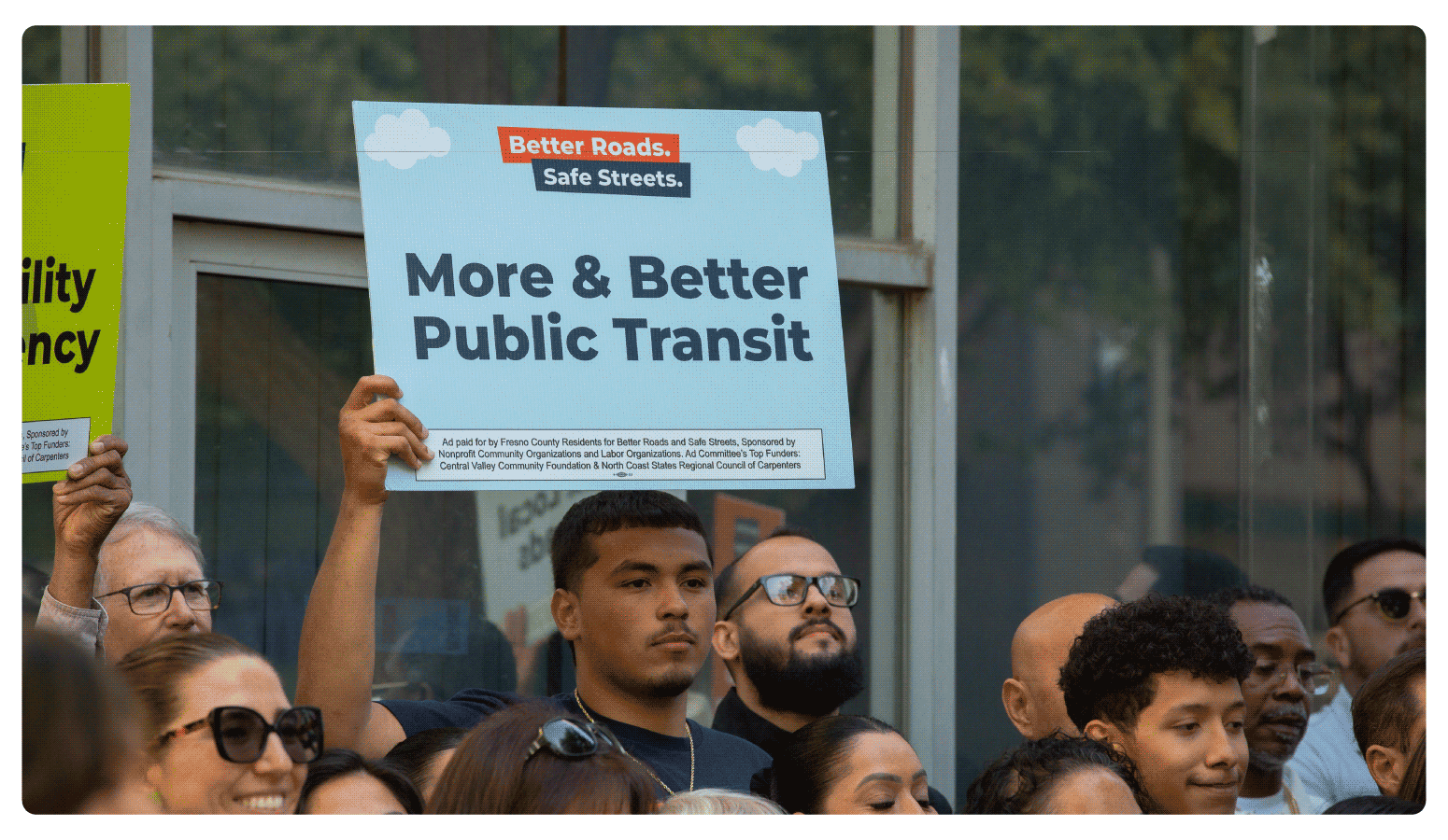 Advocate of Better Roads Safe Streets holds up a sign 